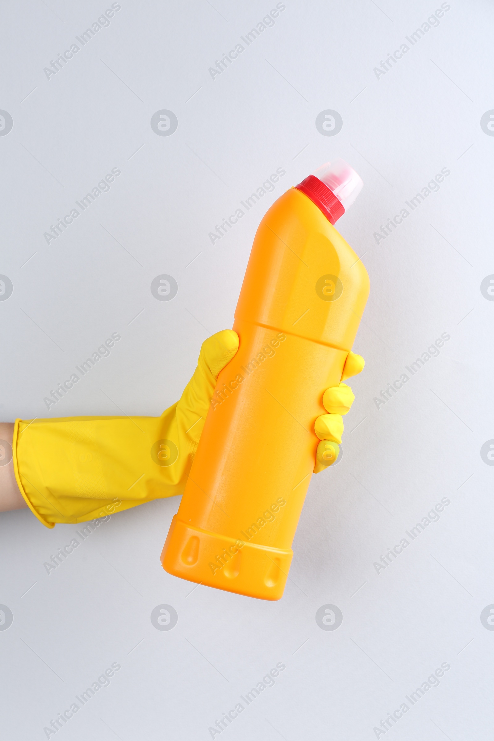 Photo of Woman holding toilet cleaner in bottle on light background, closeup