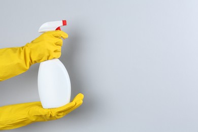 Photo of Woman holding toilet cleaner in spray bottle on light background, closeup. Space for text