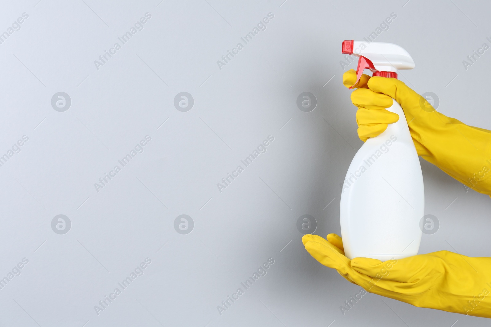 Photo of Woman holding toilet cleaner in spray bottle on light background, closeup. Space for text