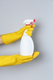 Photo of Woman holding toilet cleaner in spray bottle on light background, closeup