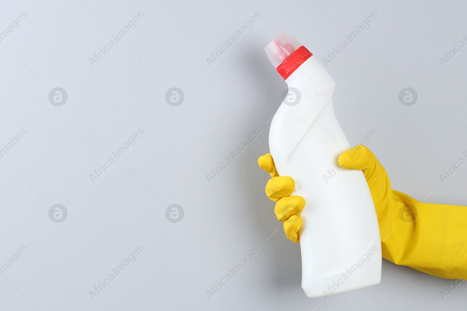 Photo of Woman holding toilet cleaner in bottle on light background, closeup. Space for text