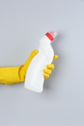 Photo of Woman holding toilet cleaner in bottle on light background, closeup