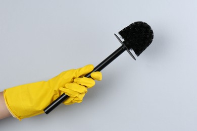 Photo of Woman holding black toilet brush on grey background, closeup. Cleaning tool