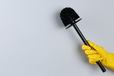 Photo of Woman holding black toilet brush on grey background, closeup. Space for text