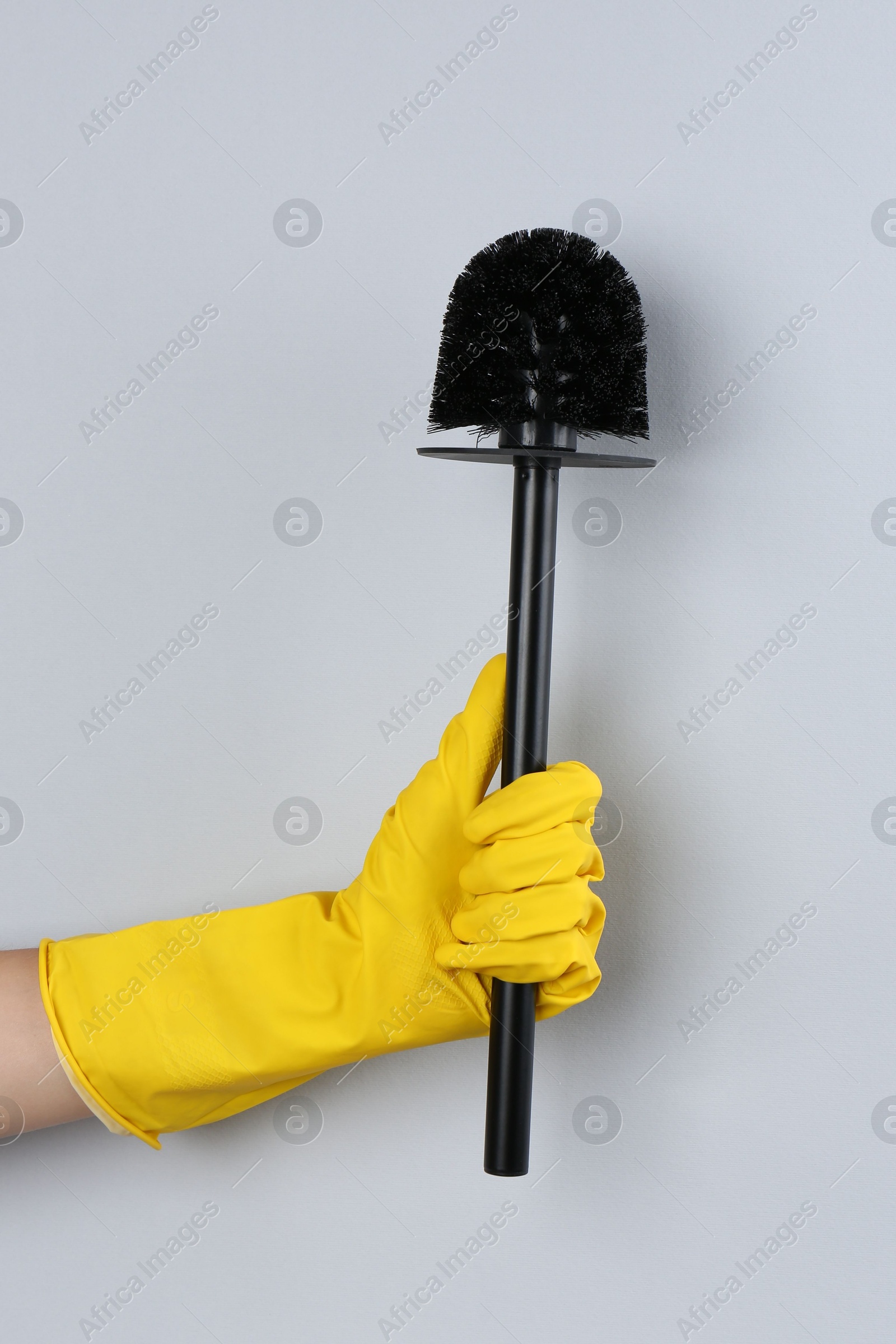 Photo of Woman holding black toilet brush on grey background, closeup. Cleaning tool