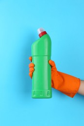 Photo of Woman holding toilet cleaner in bottle on light blue background, closeup