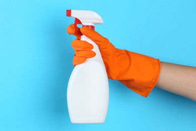 Photo of Woman holding toilet cleaner in spray bottle on light blue background, closeup