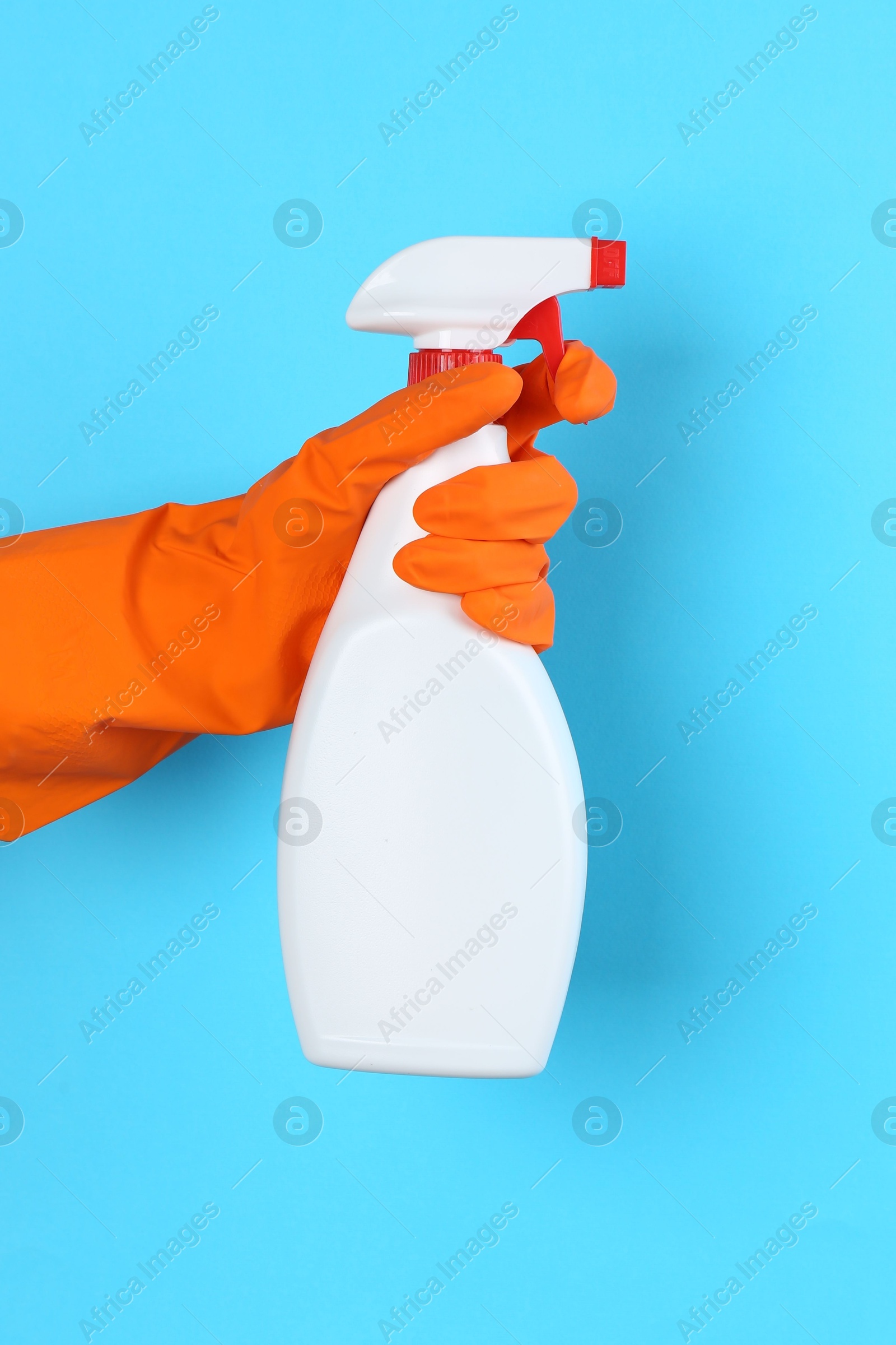 Photo of Woman holding toilet cleaner in spray bottle on light blue background, closeup