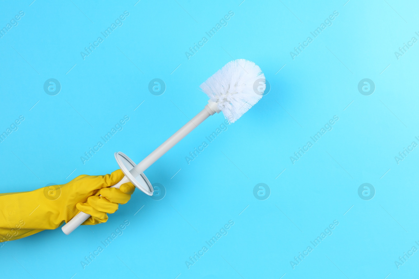 Photo of Woman holding white toilet brush on light blue background, closeup. Cleaning tool