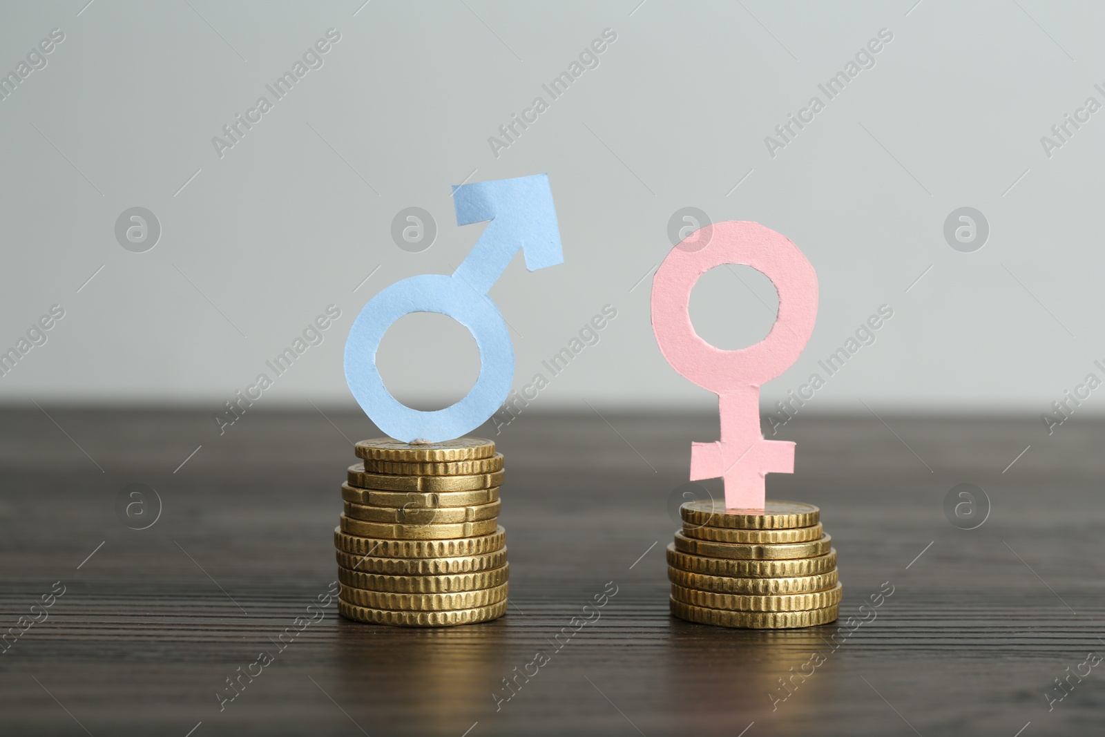 Photo of Financial inequality. Male and female symbols with coins on wooden table