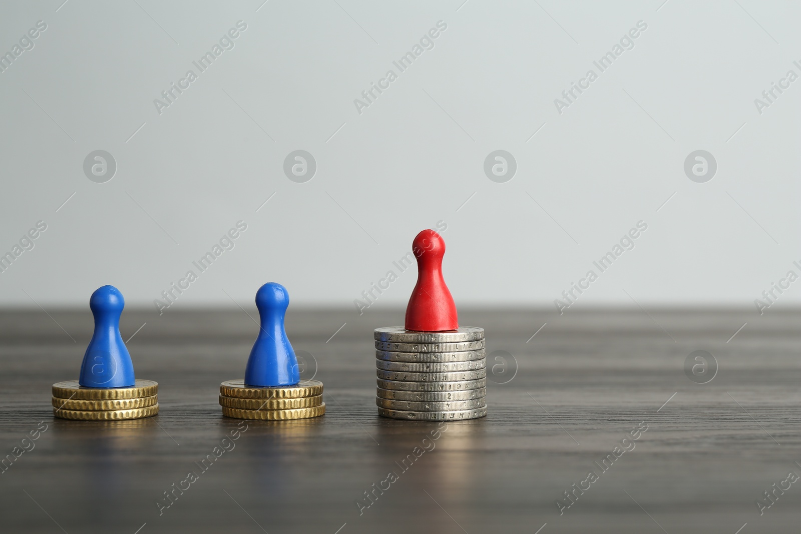 Photo of Financial inequality. Human figures and coins on wooden table