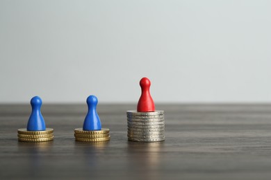 Photo of Financial inequality. Human figures and coins on wooden table