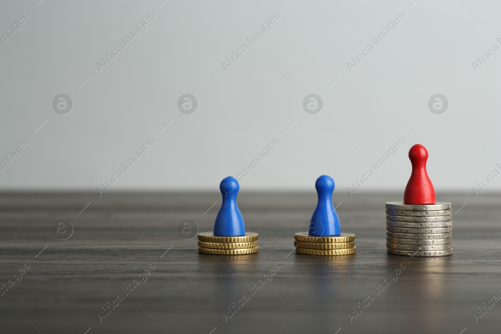 Photo of Financial inequality. Human figures and coins on wooden table