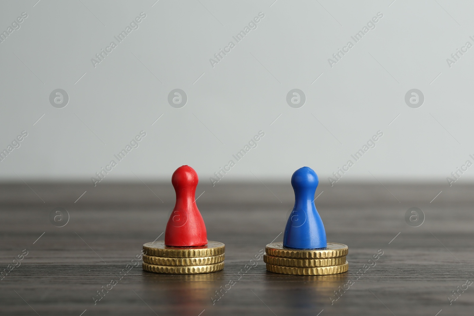 Photo of Financial equality. Human figures and coins on wooden table