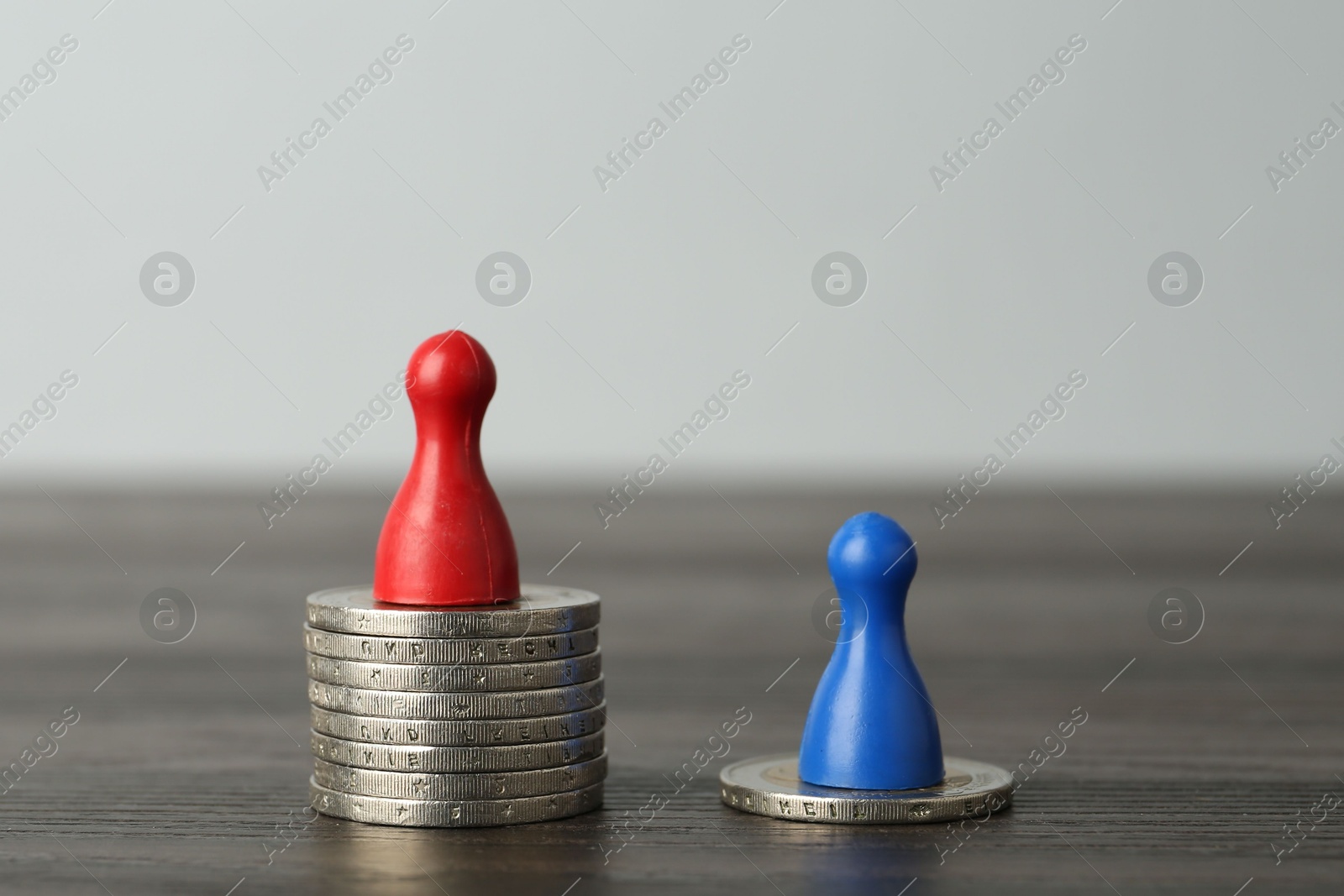 Photo of Financial inequality. Human figures and coins on wooden table