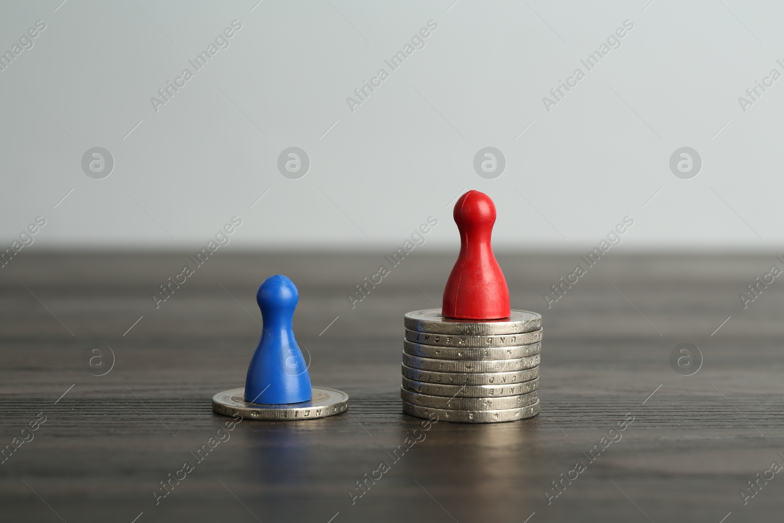 Photo of Financial inequality. Human figures and coins on wooden table