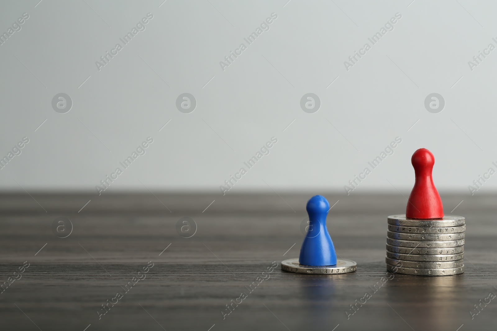 Photo of Financial inequality. Human figures and coins on wooden table. Space for text