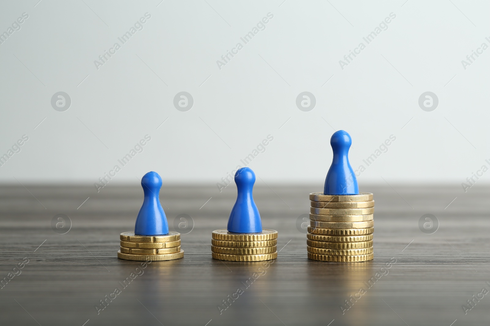 Photo of Financial inequality. Human figures and coins on wooden table