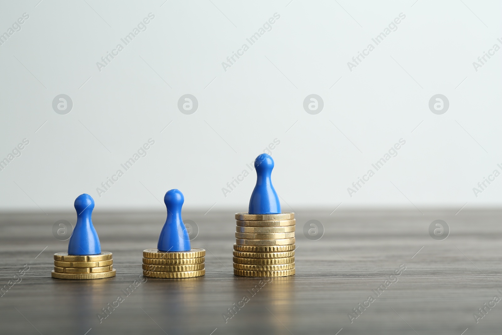 Photo of Financial inequality. Human figures and coins on wooden table. Space for text