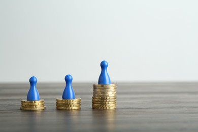 Financial inequality. Human figures and coins on wooden table. Space for text