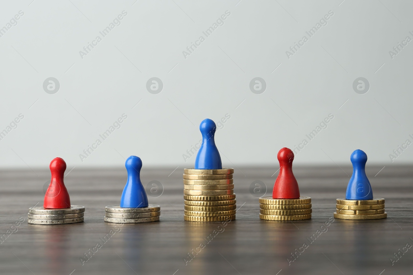 Photo of Financial inequality. Human figures and coins on wooden table