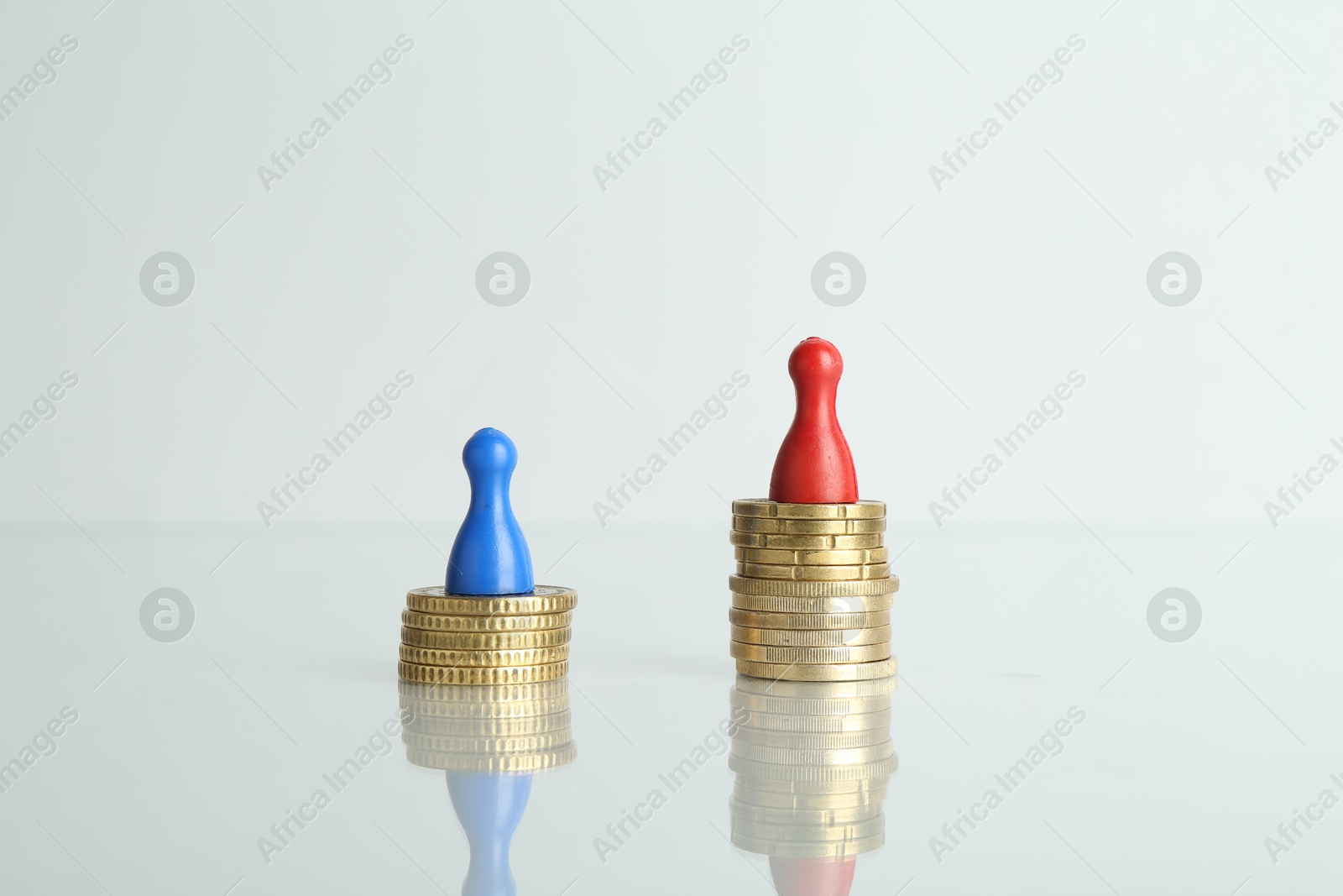 Photo of Financial inequality. Male and female figures with coins on light table