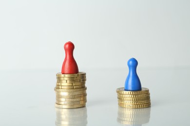 Photo of Financial inequality. Male and female figures with coins on light table