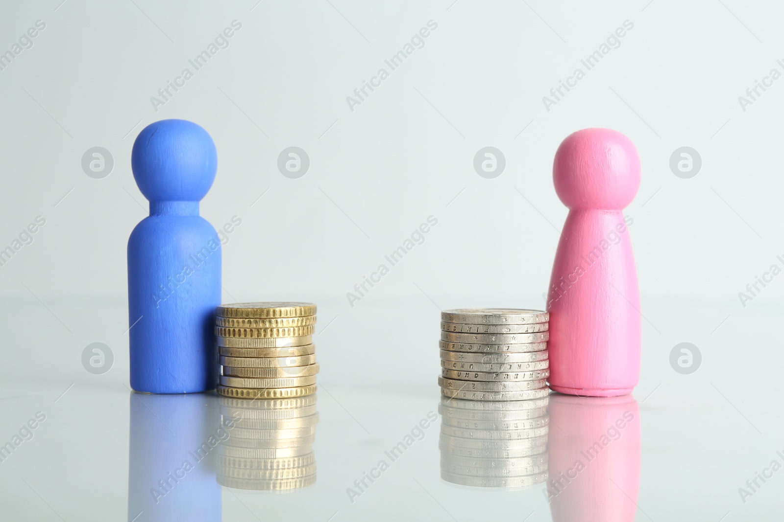 Photo of Financial inequality. Male and female figures with coins on light table