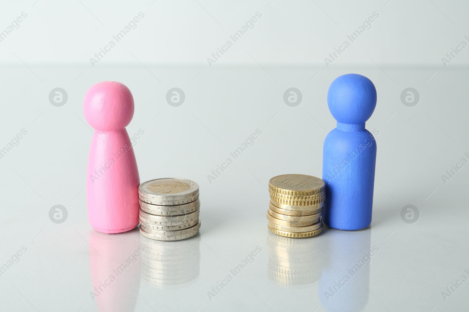 Photo of Financial inequality. Male and female figures with coins on light table