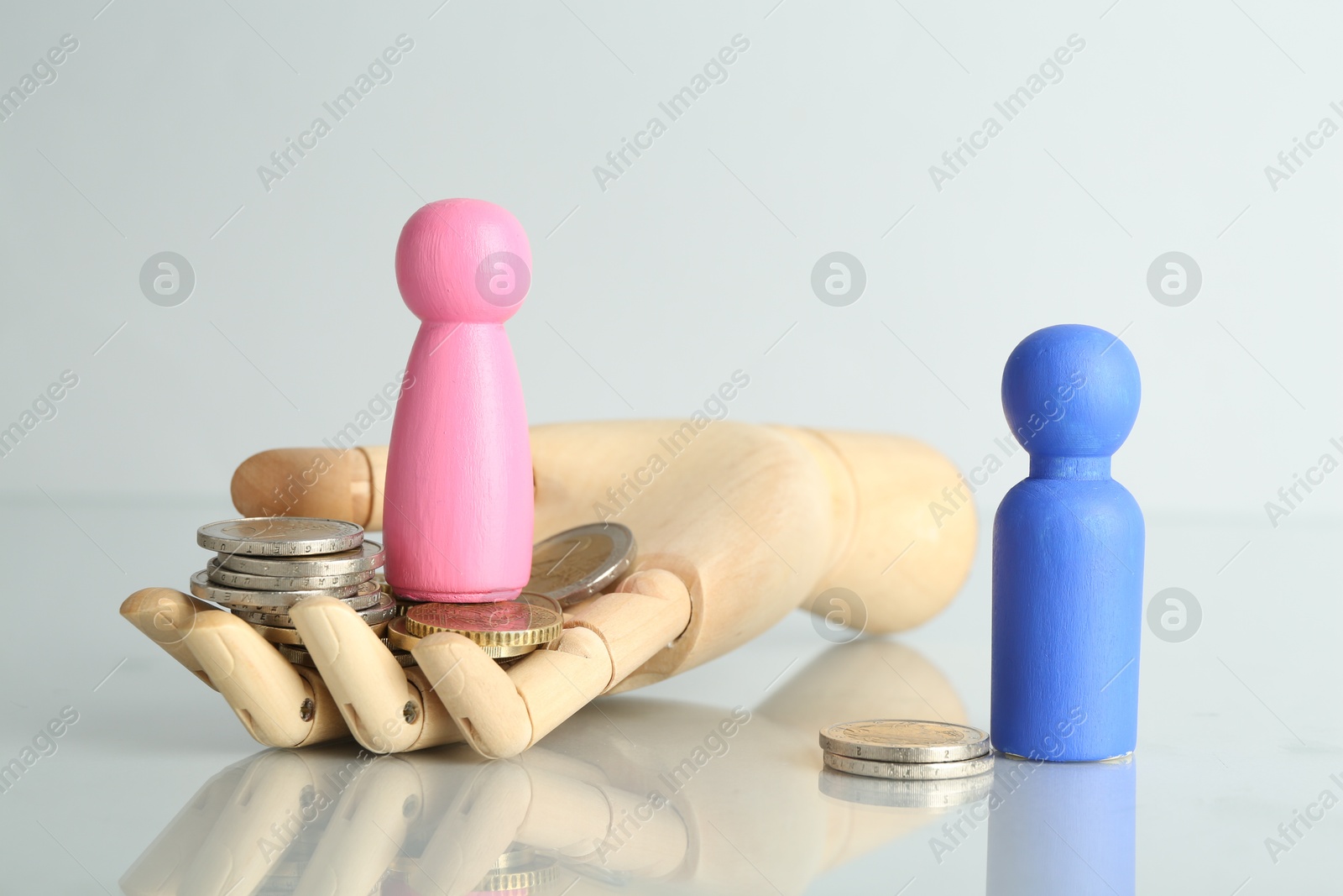 Photo of Financial inequality. Male and female figures with coins on light table