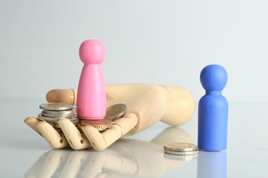 Photo of Financial inequality. Male and female figures with coins on light table