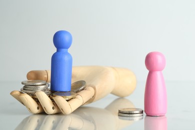 Photo of Financial inequality. Male and female figures with coins on light table