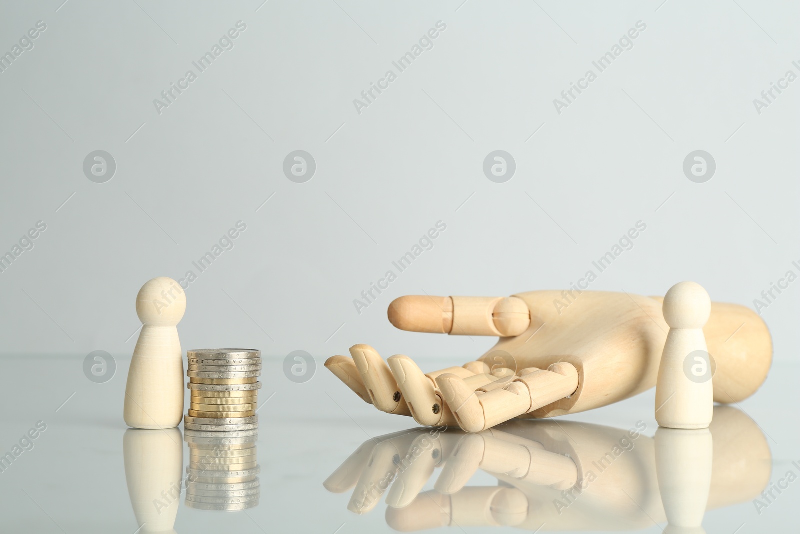 Photo of Financial inequality. Human figures, coins and wooden hand on light table