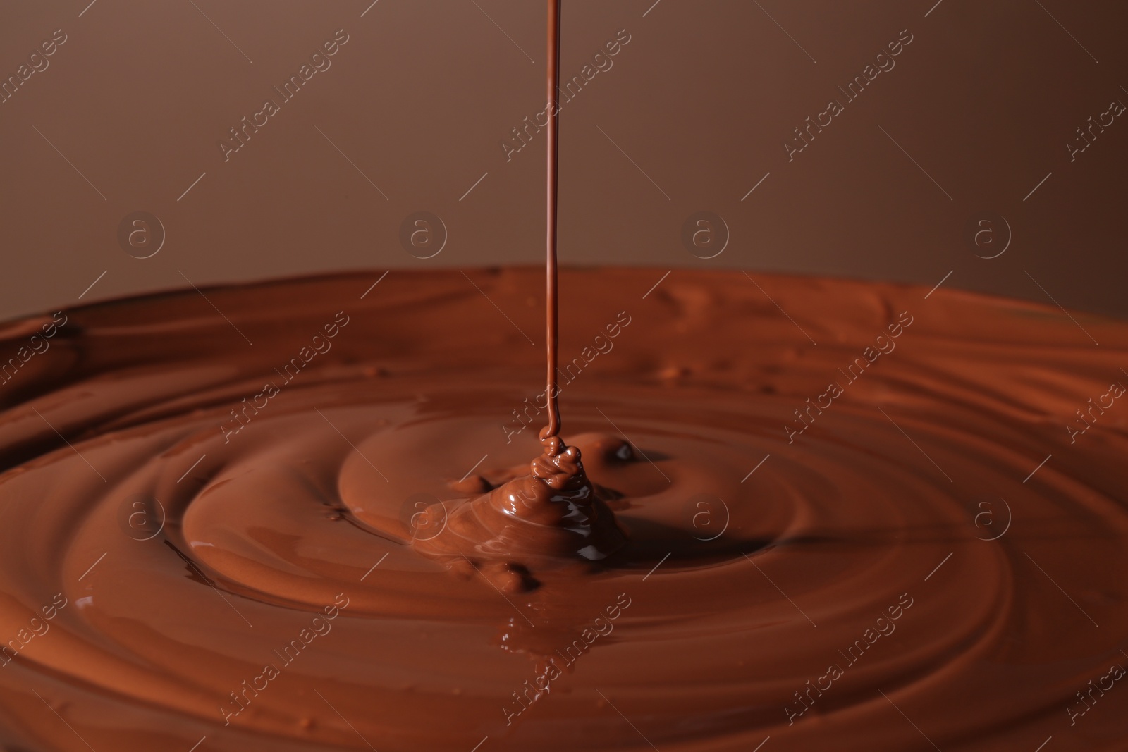 Photo of Pouring delicious melted chocolate on brown background, closeup