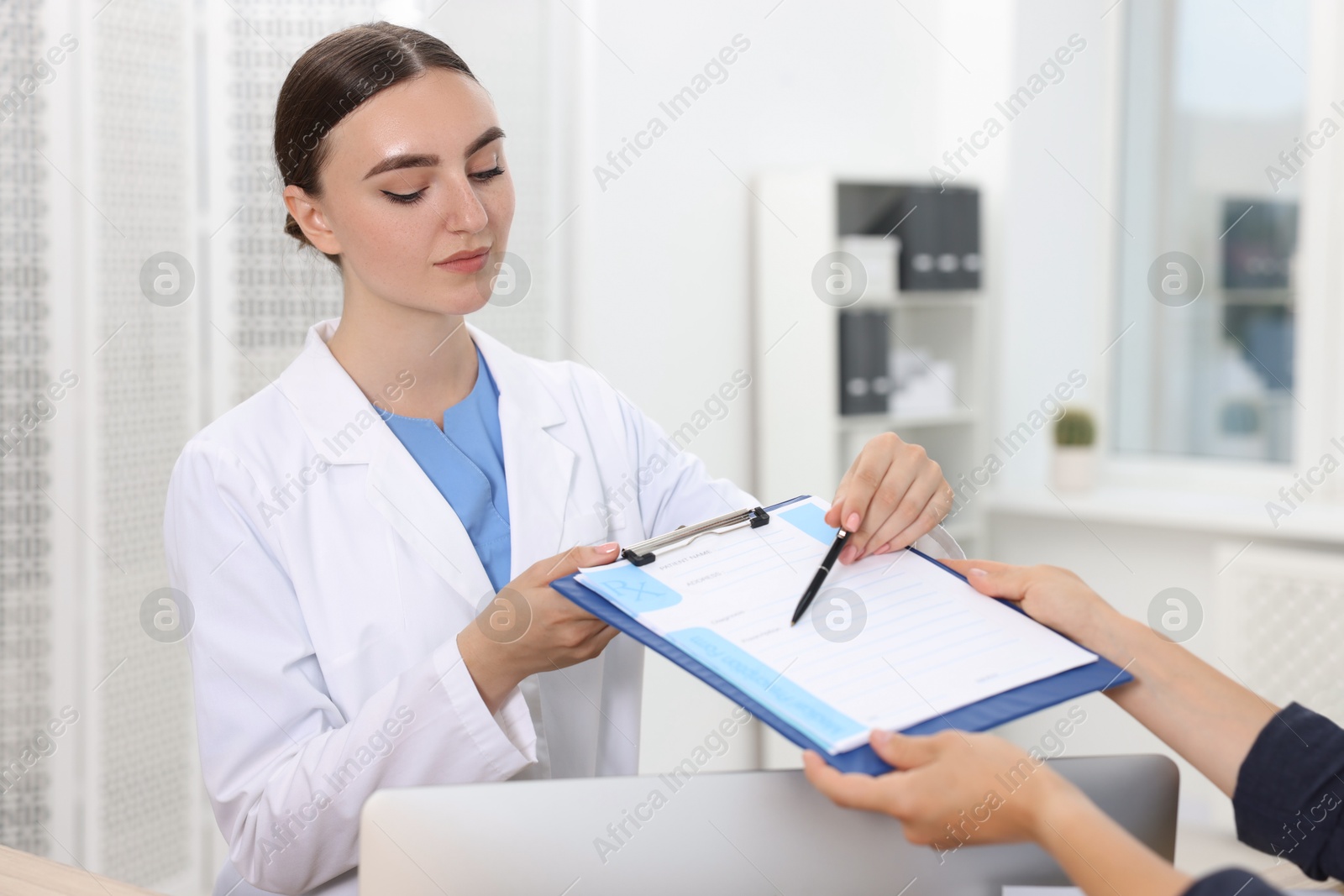 Photo of Professional receptionist working with patient at wooden desk in hospital