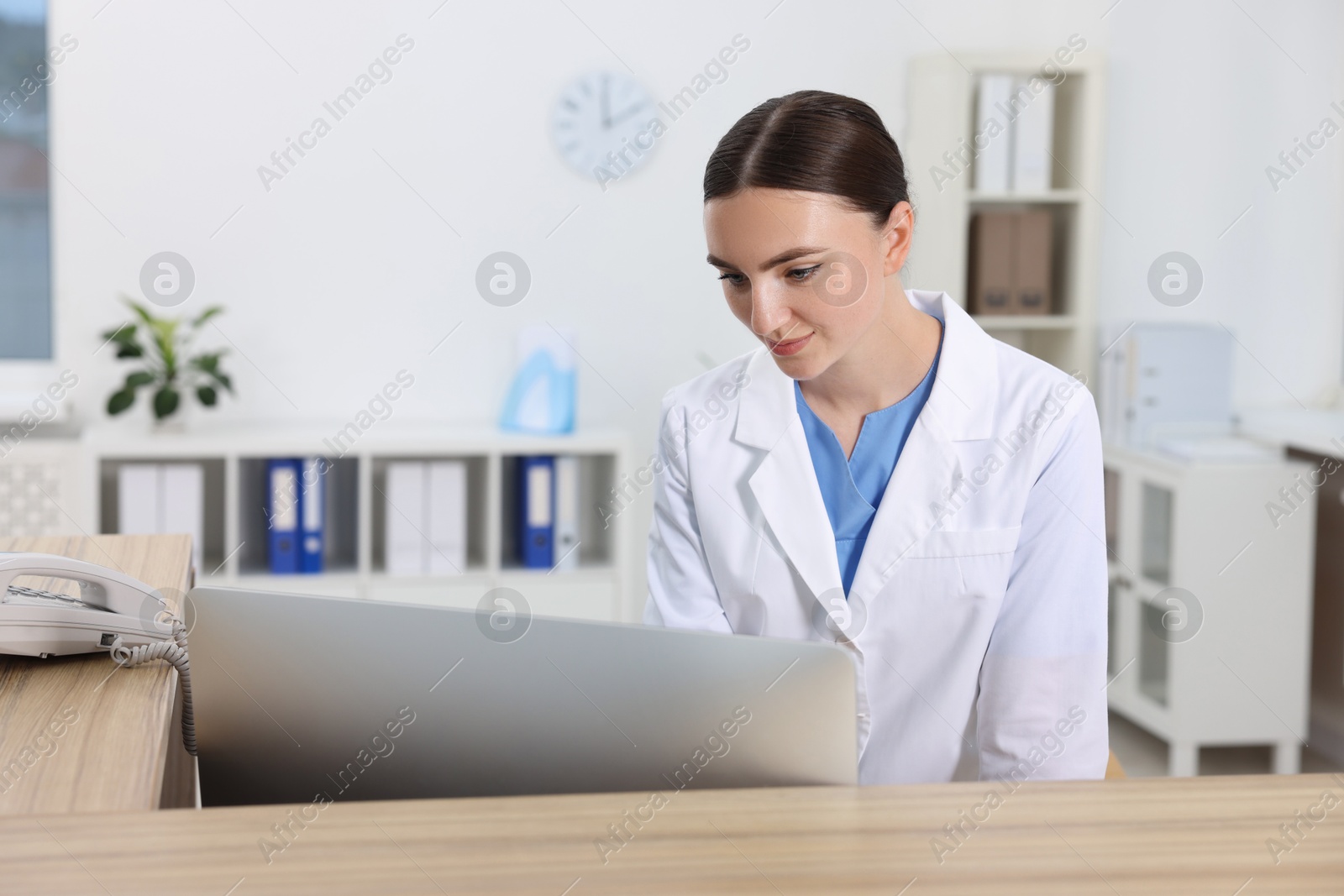 Photo of Professional receptionist working at wooden desk in hospital