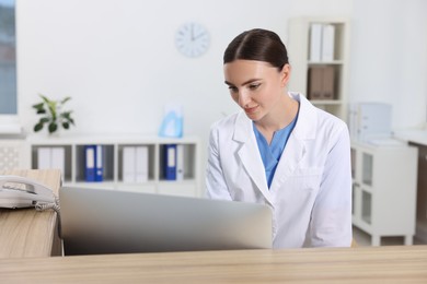 Professional receptionist working at wooden desk in hospital