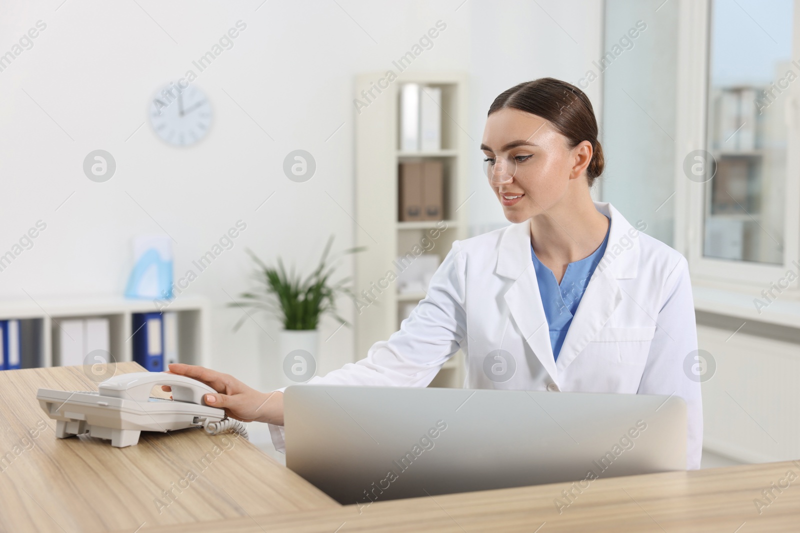 Photo of Professional receptionist working at wooden desk in hospital