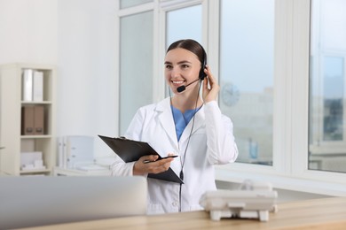 Professional receptionist working at wooden desk in hospital