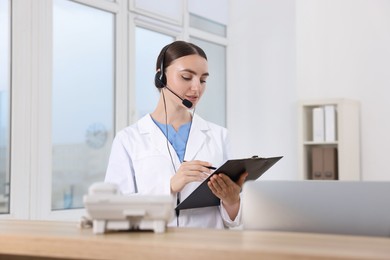 Professional receptionist working at wooden desk in hospital