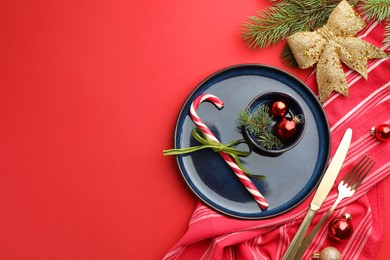 Photo of Beautiful Christmas setting with plate, elegant cutlery and festive decor on red table, flat lay. Space for text