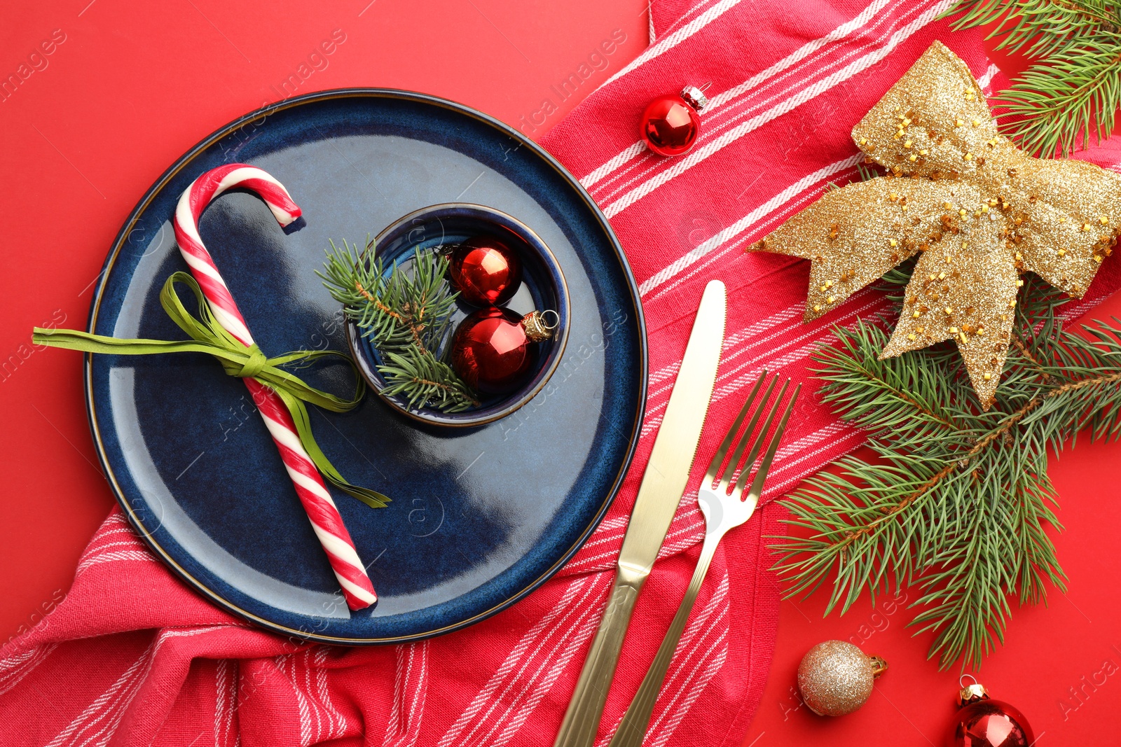 Photo of Beautiful Christmas setting with plate, elegant cutlery and festive decor on red table, flat lay