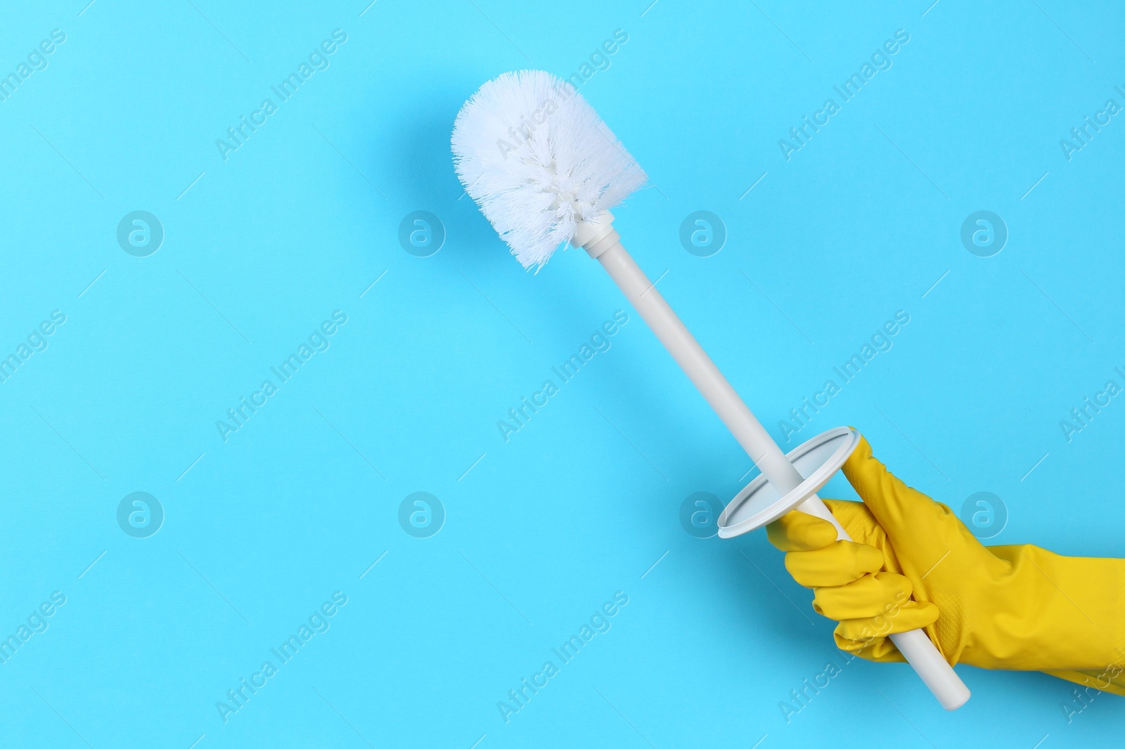 Photo of Woman holding white toilet brush on light blue background, closeup. Cleaning tool