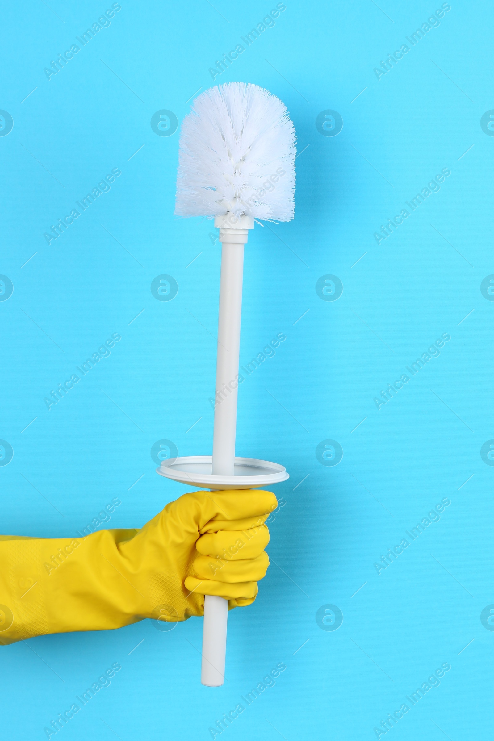 Photo of Woman holding white toilet brush on light blue background, closeup. Cleaning tool