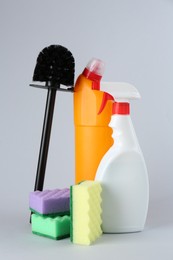 Photo of Different toilet cleaners, sponges and brush on grey background