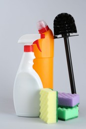 Photo of Different toilet cleaners, sponges and brush on grey background