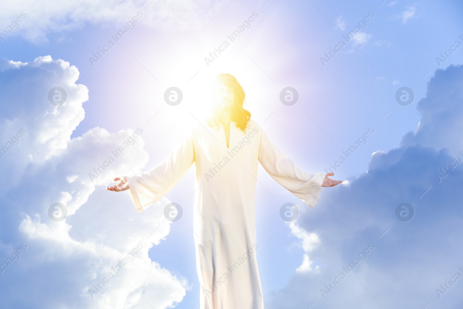 Image of Jesus Christ in sunlight among clouds in sky