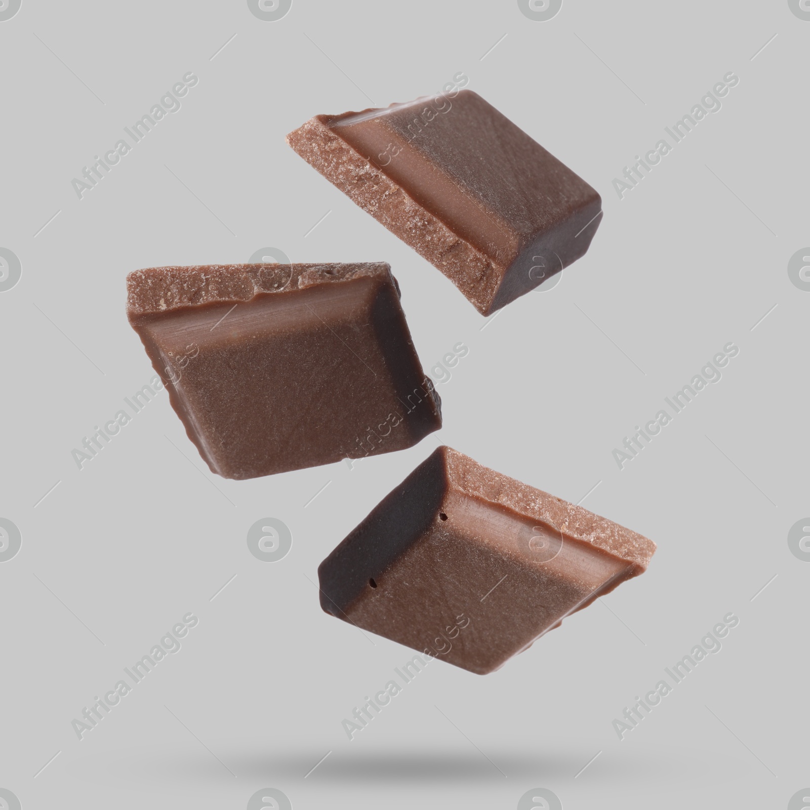 Image of Pieces of sweet chocolate falling on grey background