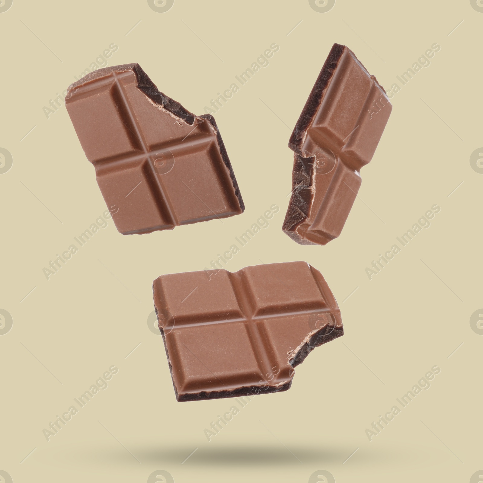 Image of Pieces of sweet chocolate falling on color background