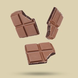 Pieces of sweet chocolate falling on color background